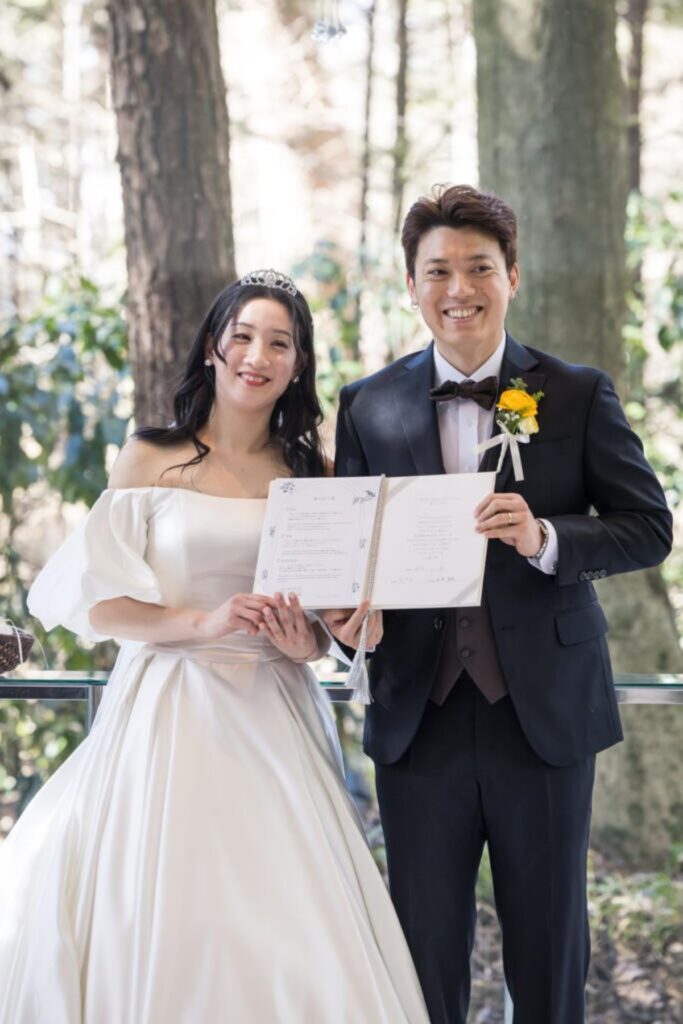 自然に囲まれたチャペルで、結婚証明書を手に最高の笑顔。二人の絆が深まる特別な一枚。