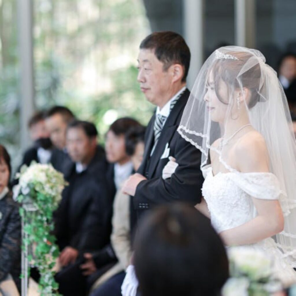 軽井沢の四季が祝福の背景に。天然大理石に光が反射し、花嫁姿が輝く透明感あふれる挙式。雨の日も美しい誓いの場。
