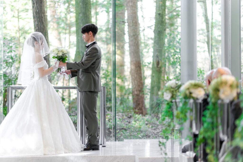 軽井沢の四季が祝福の背景に。天然大理石に光が反射し、花嫁姿が輝く透明感あふれる挙式。雨の日も美しい誓いの場。