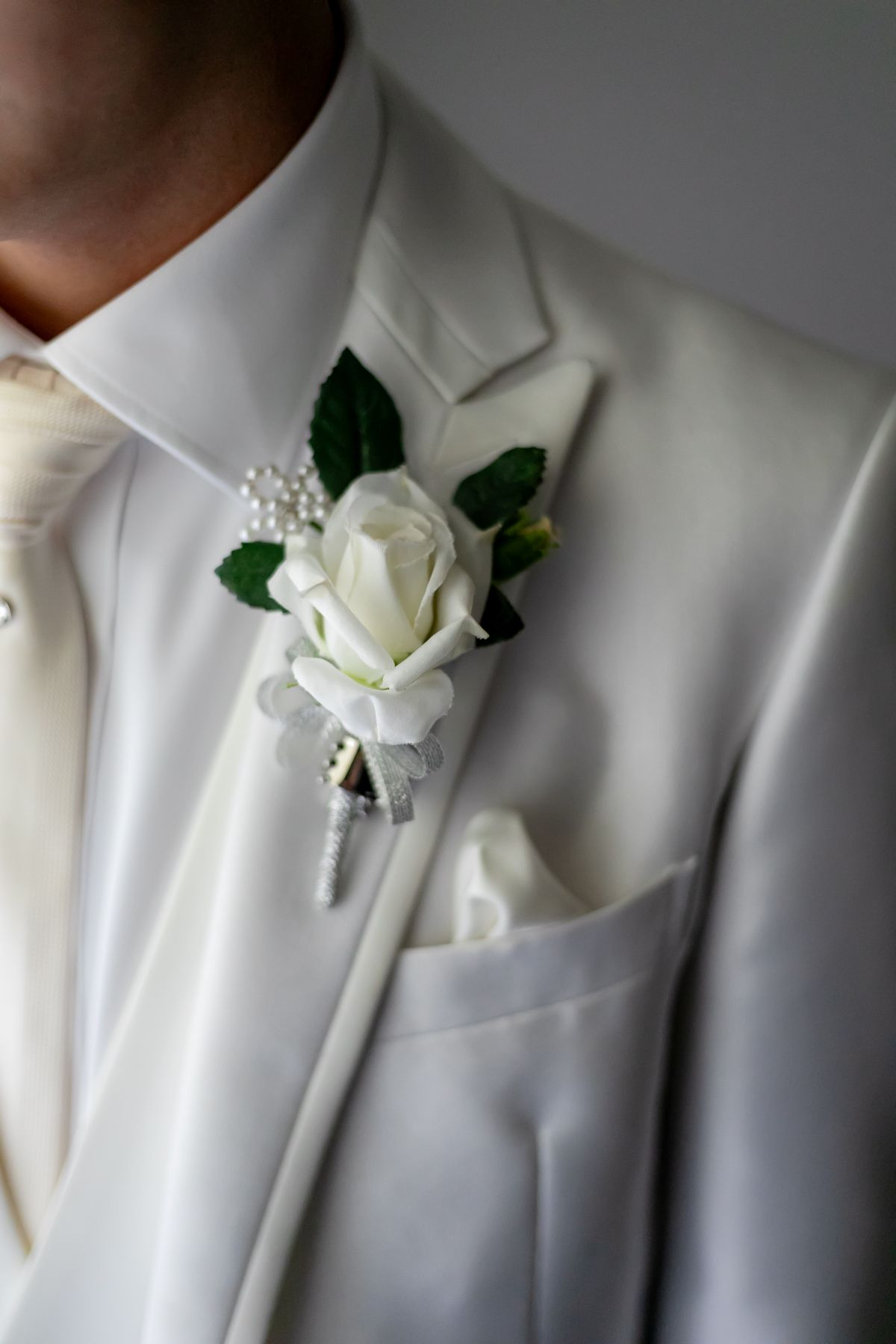 細部に宿る、新郎のこだわり。洗練されたホワイトタキシードとブートニアが、主役の風格を演出します。アネーリ軽井沢で叶える、トータルコーディネート。