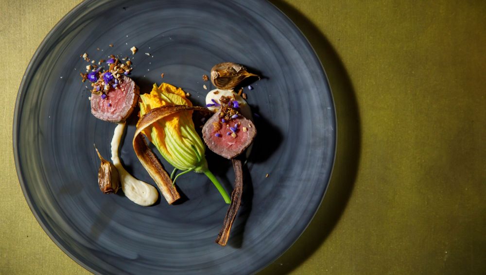アネーリ軽井沢の信州フレンチのメイン。低温調理された信州牛と花ズッキーニ、黒ニンニクを添えた、芸術的な一皿。料理の質にこだわるカップルへ贈る最上級のおもてなし。