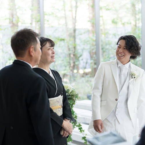 挙式前の緊張と喜びが入り混じるひととき。新郎様とご両親の間に流れる優しい笑顔と確かな絆が、お二人らしいアットホームな結婚式を彩ります。
