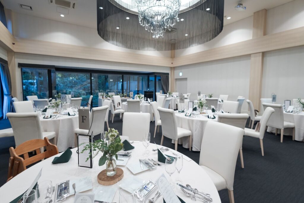 軽井沢の自然光が降り注ぐモダンな空間。白いテーブルクロスと、濃いグリーンのアクセントが織りなす洗練されたテーブルコーディネートが、お二人らしい祝宴を演出します。