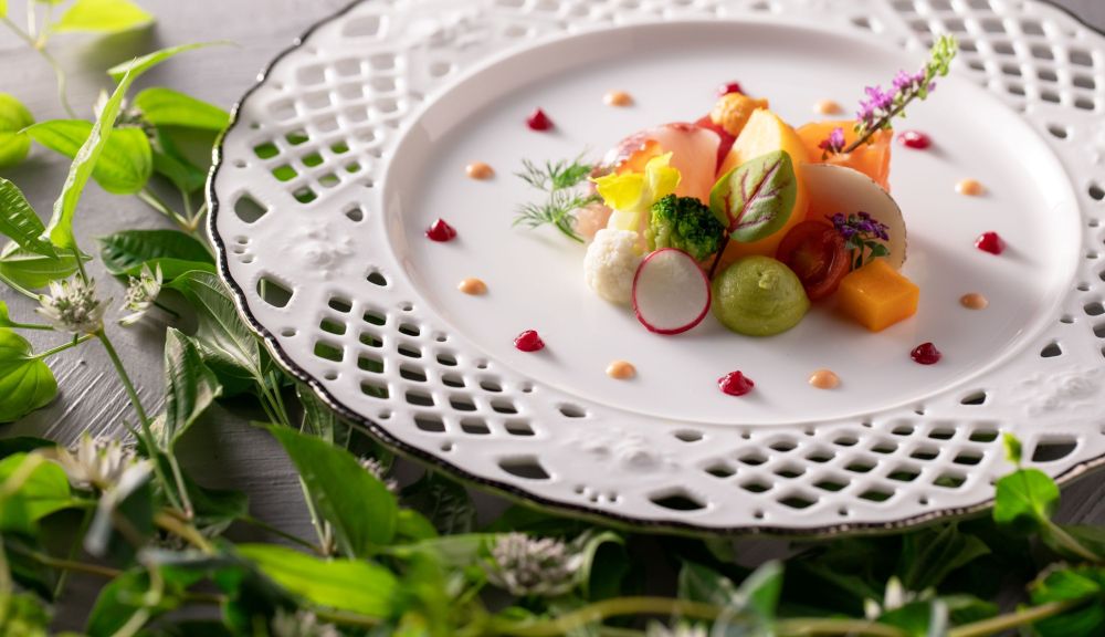 アネーリ軽井沢の結婚式を彩るフレンチのオードブル。旬の軽井沢高原野菜やフルーツ、ハーブを繊細なレース皿にアートのように盛り付けた一皿。女性ゲストに人気の鮮やかな料理。