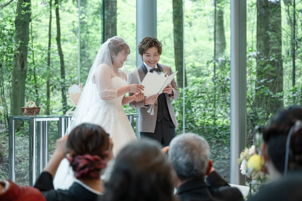 軽井沢の森に包まれた挙式!自然光が差し込むアネーリ軽井沢で、笑顔で誓いを立てる二人。