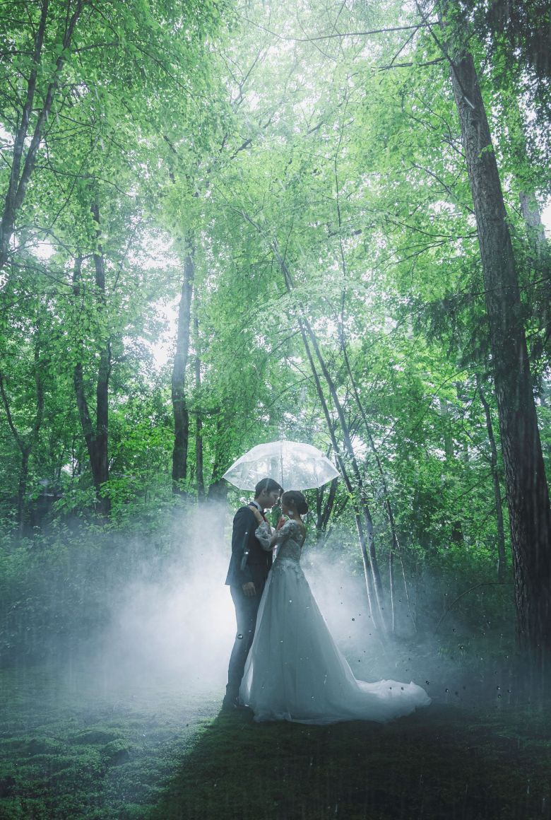 アネーリ軽井沢の森での幻想的な前撮り。雨の中、傘の下で抱き合う新郎新婦のロマンチックなウェディングフォト・フォトウェディング