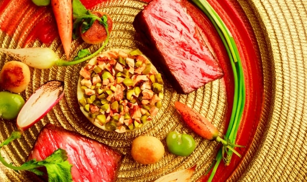 アネーリ軽井沢の婚礼料理を飾るメインディッシュ。鮮やかな信州プレミアム牛と高原野菜を、黄金の皿にアートのように盛り付け。贅沢な美食で叶える最上級のおもてなしの結婚式。