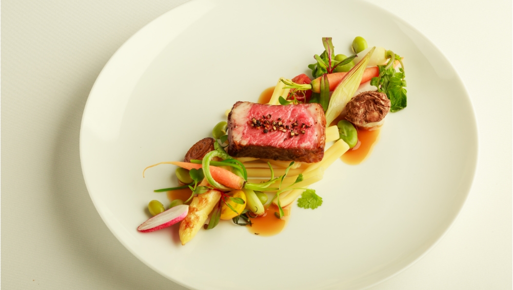 アネーリ軽井沢の婚礼フレンチで提供される、信州牛のメイン料理。低温調理された肉と彩り豊かな軽井沢の高原野菜を添えた、芸術的な一皿。料理の質にこだわるカップルへ贈る美食体験。