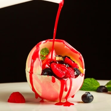 アネーリ軽井沢の婚礼フレンチを締めくくるデザート演出。温かいベリーソースをかけると溶け出すホワイトチョコレートの球体。驚きと感動を与えるサプライズデザートで、軽井沢ウェディングの祝宴を華やかに。