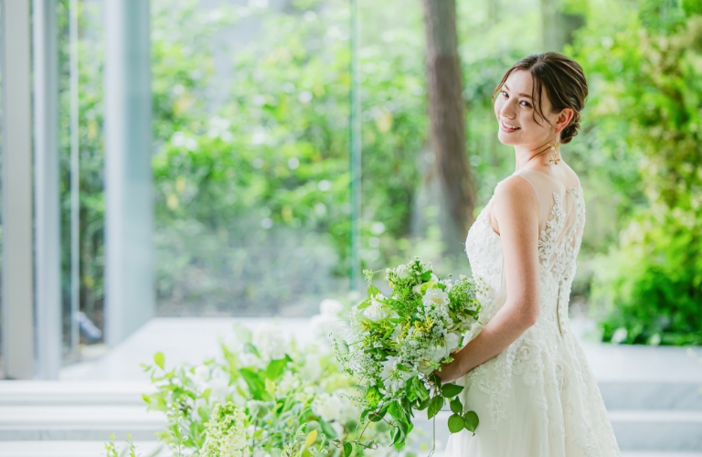 軽井沢の森に佇むアネーリ軽井沢のチャペルでの花嫁姿。ナチュラルなグリーンブーケとウェディングドレスの繊細なレースが、開放的な空間に美しく調和。リゾート婚の夢を叶える一枚。