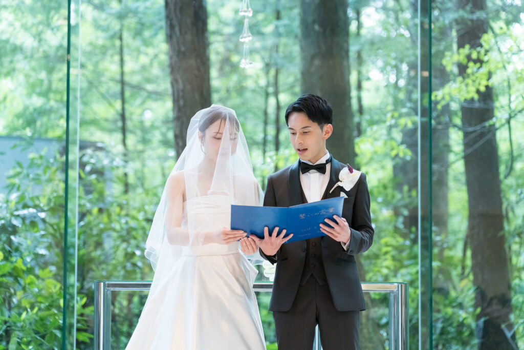 森の緑に包まれたガラスのチャペルで、誓いの言葉を読み上げるふたり。光と自然に見守られる神聖な空間で、感動的なリゾートウェディングを。