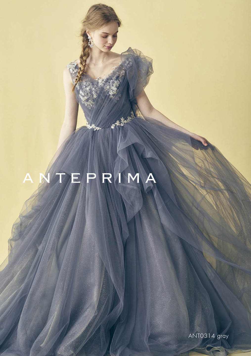 アネーリ軽井沢提携のANTERPRIMA (アンテプリマ) のカラードレス (品番: ANT0314/グレー)。アシンメトリーなフリルと幾重にも重ねられたチュールが特徴の大人可愛いプリンセスライン。胸元の立体的な刺繍とビジューベルトが華やかで、軽井沢の開放的なロケーションに映える1着。