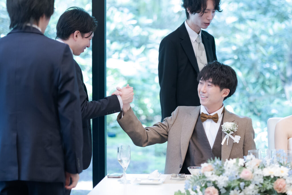 新郎と友人の熱い握手!ゲストとの距離が近いアットホームな結婚式。軽井沢の特別な空間で、感謝を伝えるパーティーを。