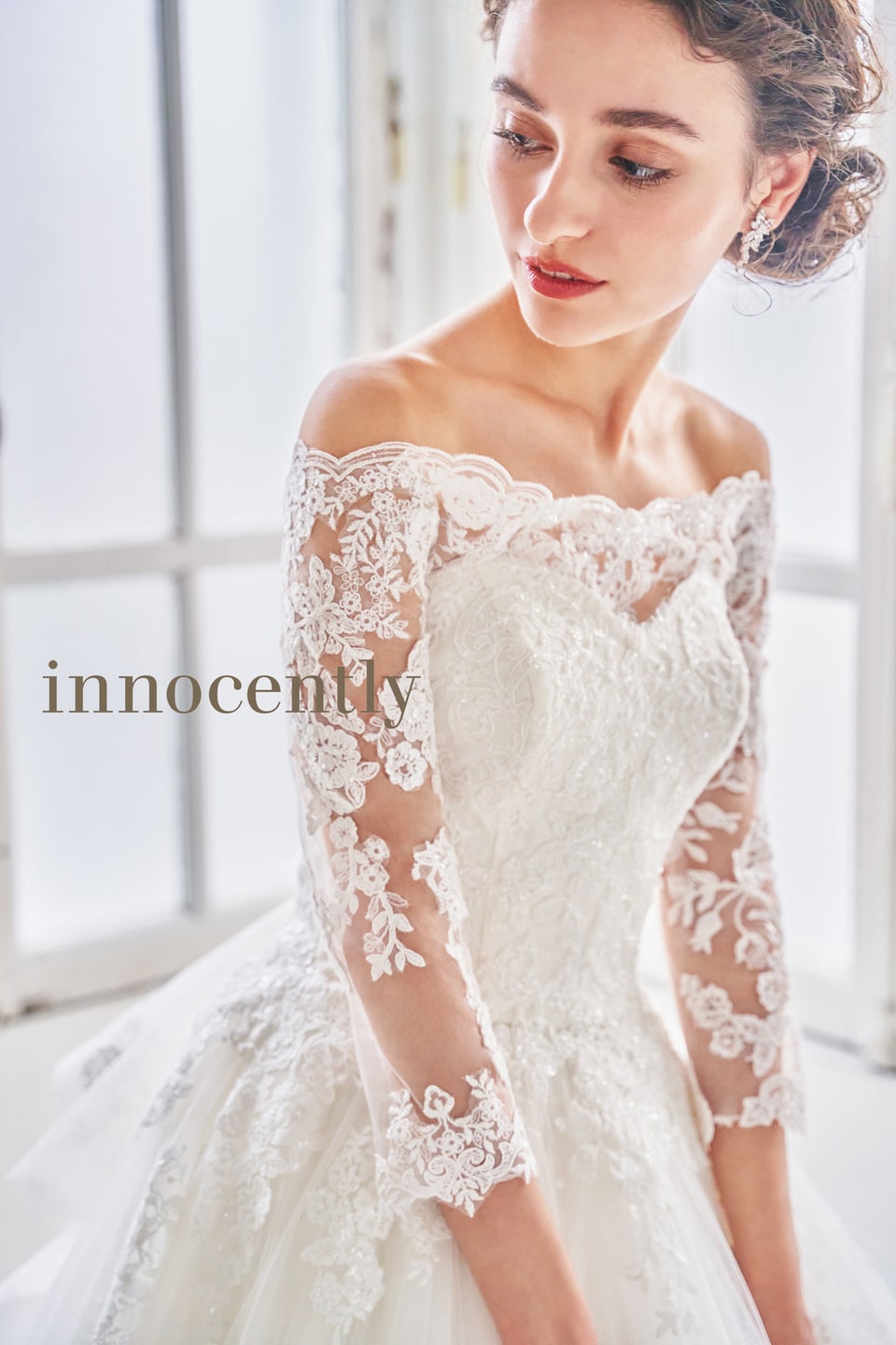 innocently(イノセントリー)のオフショルダー・長袖ウェディングドレス。繊細な総レースとチュールが織りなす透明感が魅力。軽井沢の柔らかな自然光の中で、可憐な花嫁姿を演出するインポート風ドレス。