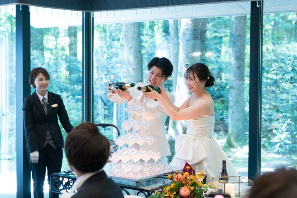 軽井沢の緑と自然光が彩る、華やかなシャンパンタワー演出。お二人とゲストの未来を祝う光輝く瞬間です。開放的な会場で、記憶に残るウェディングパーティーを。