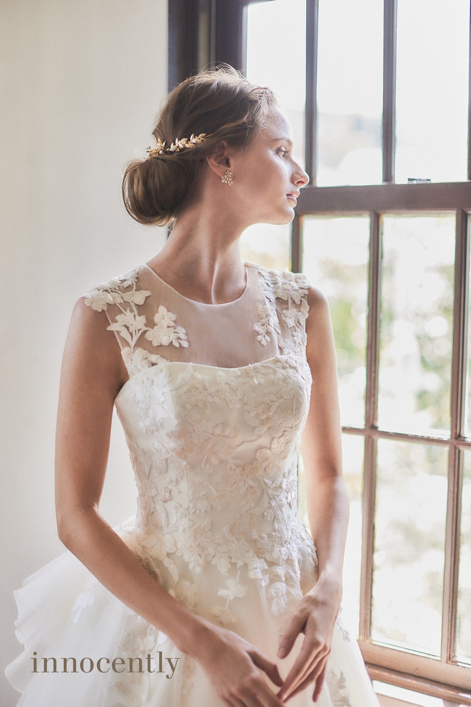 【innocently(イノセントリー)】のウェディングドレス。ハイネックのレースデザインと大柄なフラワー刺繍がクラシカルなAライン。アネーリ軽井沢のアンティークな窓辺に立つ清楚な花嫁姿。