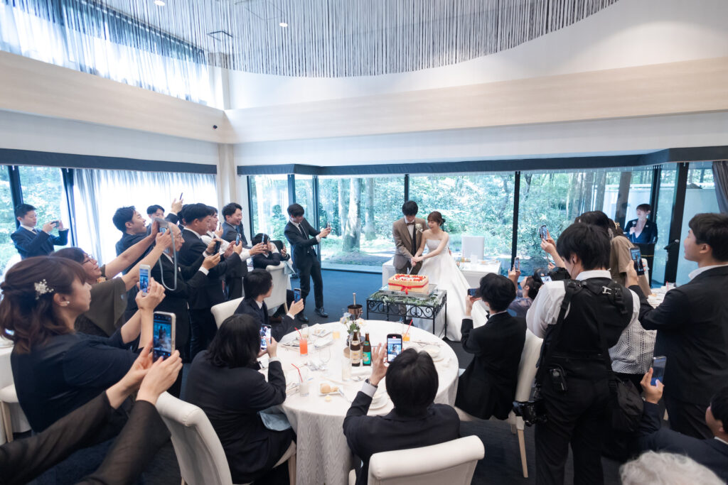 軽井沢の森に囲まれた会場で、ゲストの歓声に包まれるケーキ入刀。自然光と一体感が魅力の貸切空間で、心に残るウエディングを。