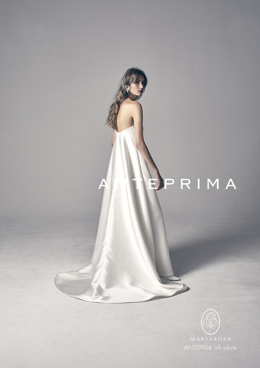 アネーリ軽井沢提携ドレス。ANTERPRIMA (アンテプリマ) のサテンウェディングドレス (品番: ANT0904) の後姿。上質なサテンの光沢が美しいバックスタイルと、流れるようなAラインのロングトレーンが魅力。軽井沢のクラシカルなチャペルでの挙式で、ゲストを魅了するミニマルでスタイリッシュな大人花嫁向けの1着。