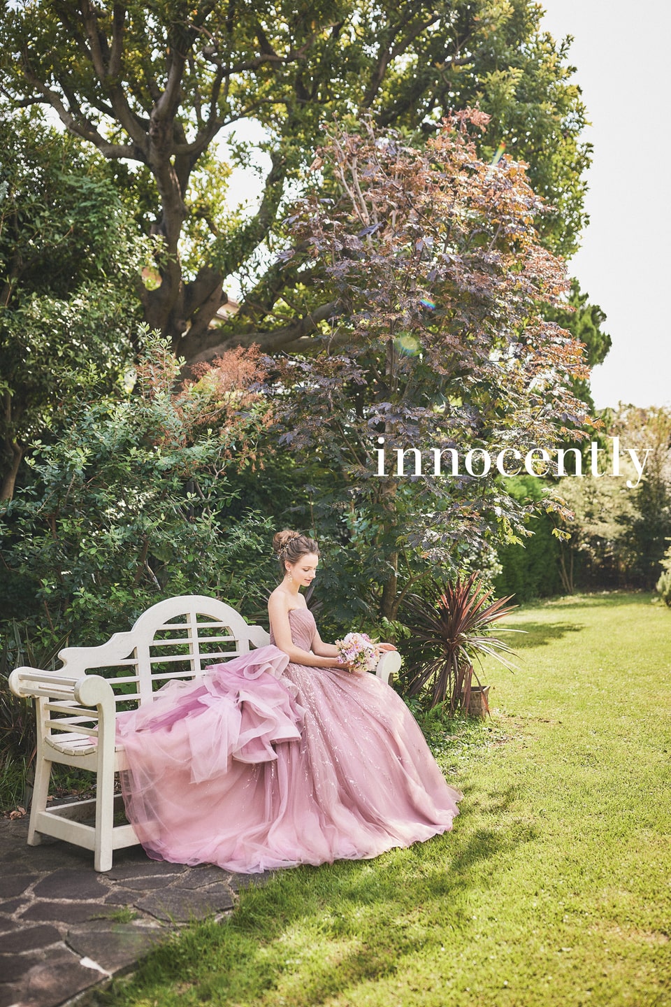 アネーリ軽井沢提携イノセントリーのダスティピンクのカラードレス。グリッターとオーガンジーのフリルが華やかなプリンセスラインのドレスは、軽井沢のガーデンのベンチに座るロマンティックなお色直しシーンを演出します。