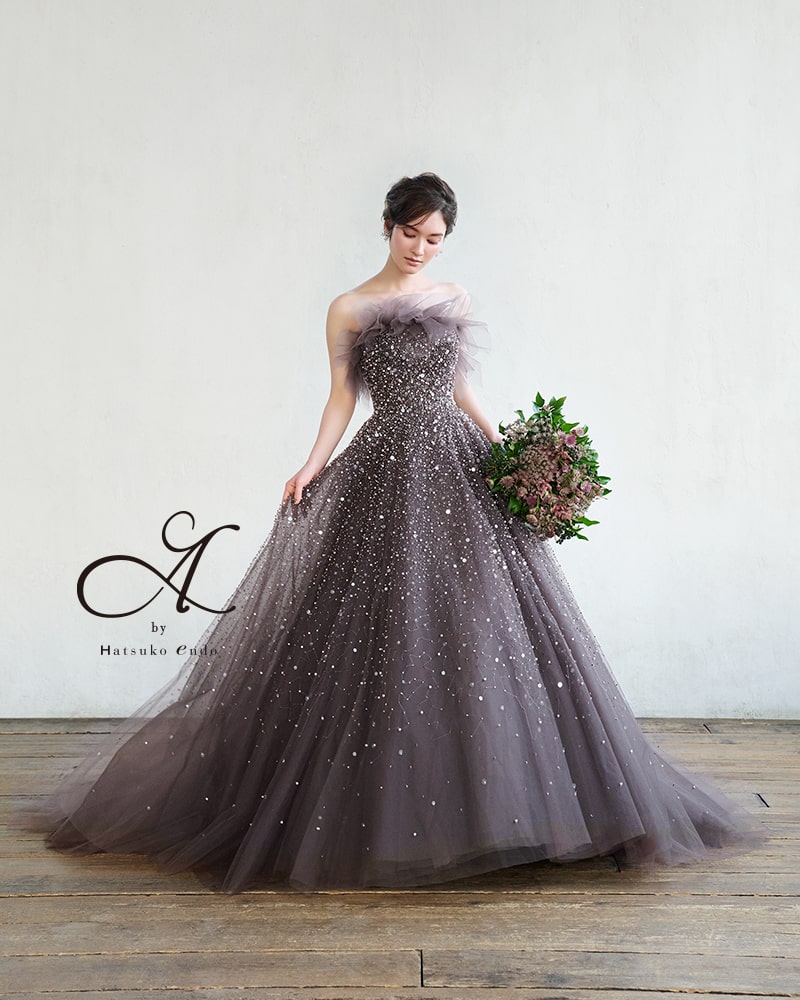 アネーリ軽井沢提携ドレス。A by Hatsuko Endo (ハツコエンドウ) のダークグレーのカラードレス。全身に散りばめられたグリッターと、アシンメトリーなフリルネックが特徴。軽井沢のナイトウェディングやお色直しで、圧倒的な輝きを放つ主役級のドレス。大人っぽく洗練された花嫁におすすめ。