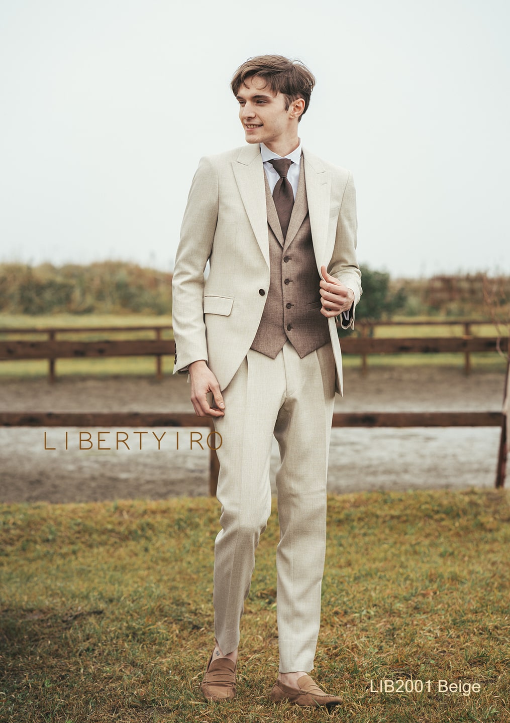 アネーリ軽井沢提携。LIBERTYIRO (リバティイロ) のベージュのタキシード (品番: LIB2001)。明るいトーンのジャケットと、ブラウンのベストの配色がお洒落なスリーピース。軽井沢のガーデンやテラスでの結婚式、前撮りに最適。花嫁のウェディングドレスをより引き立てる柔らかな印象の新郎衣装。