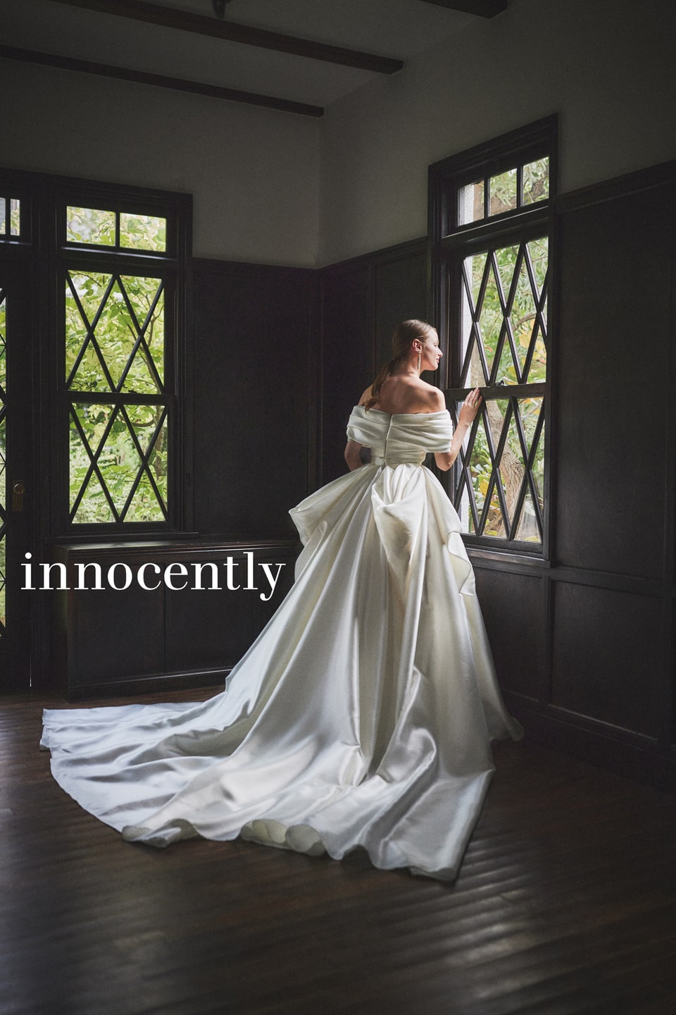 innocently(イノセントリー)のサテンドレス。背中の大きなリボンとティアードフリルが印象的なバックスタイル。オフショルダーでデコルテを美しく見せる、軽井沢のクラシカルな結婚式に合う一着。