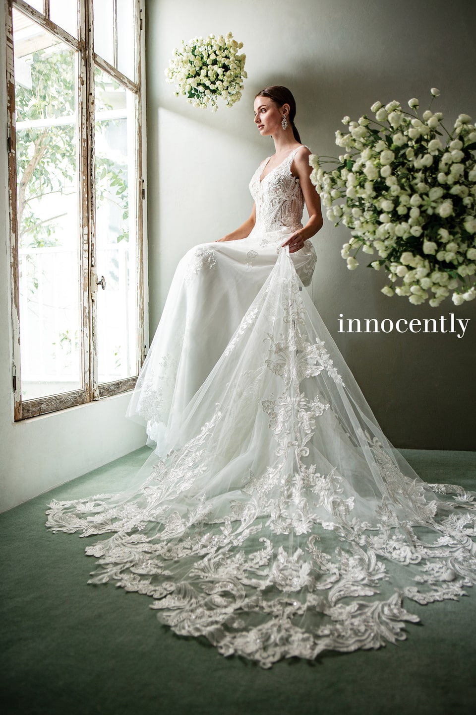 【innocently(イノセントリー)】のウェディングドレス。ノースリーブのマーメイドラインに、大柄なレース刺繍が特徴的なロングトレーン。アネーリ軽井沢の自然光が差し込む窓辺に映える一着。