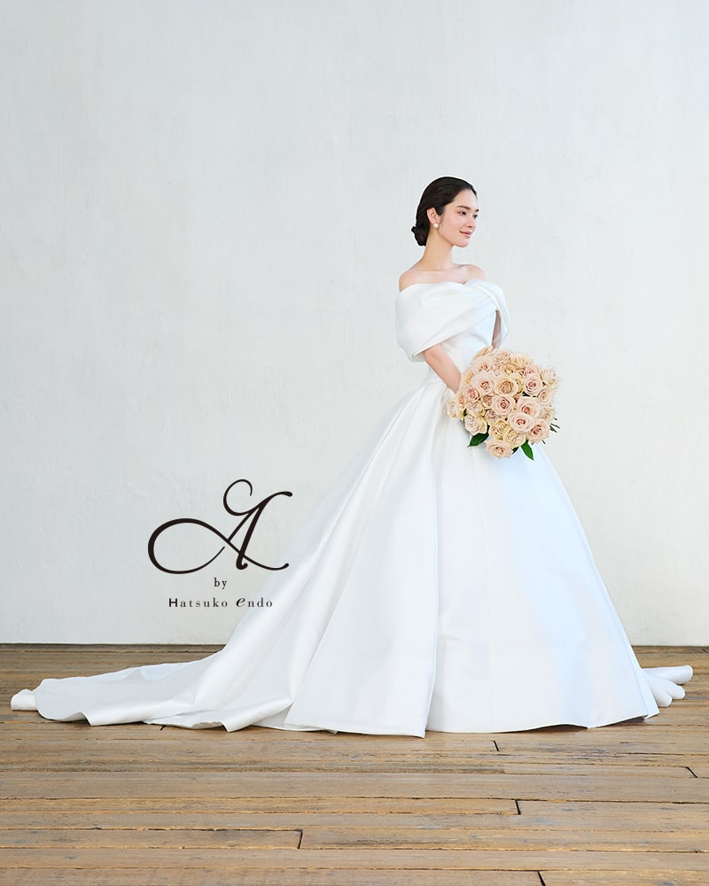 A by Hatsuko Endo(ハツコエンドウ)のオフショルダー・サテンウェディングドレス。上品な光沢のミカドサテンを贅沢に使ったAラインで、花嫁をクラシカルに演出。アネーリ軽井沢の上質な空間に似合う一着です。