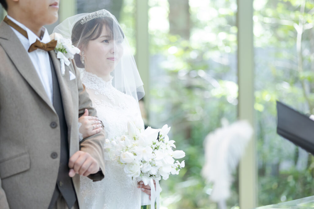 軽井沢のチャペルへ一歩踏み出す、緊張と感動に満ちた瞬間。自然光が花嫁を優しく包み込みます。リゾートウェディングでおもてなしの挙式を。