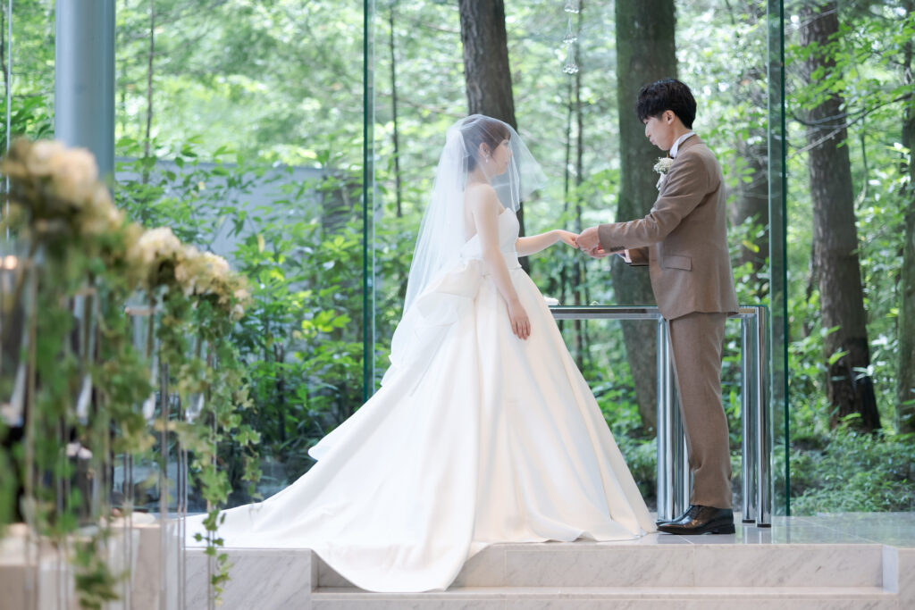 軽井沢の緑の中で愛を誓う指輪交換の瞬間。お二人の永遠の絆を、厳かで美しい独立型チャペルで。感動のセレモニーをサポート。