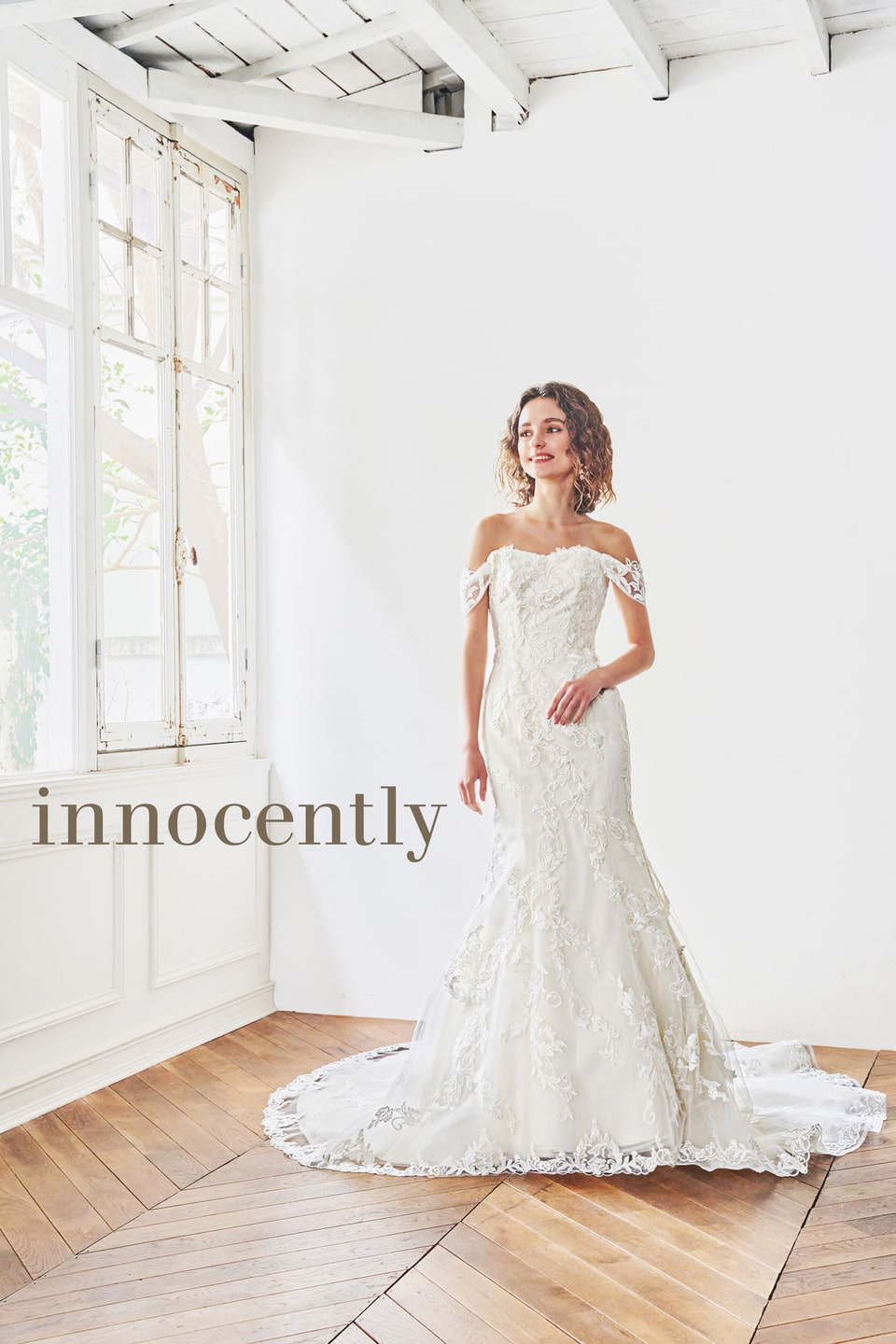 【innocently(イノセントリー)】のウェディングドレス。オフショルダーと全身の繊細なレース刺繍が特徴のマーメイドライン。明るい自然光が差し込むアネーリ軽井沢の会場に最適な一着。