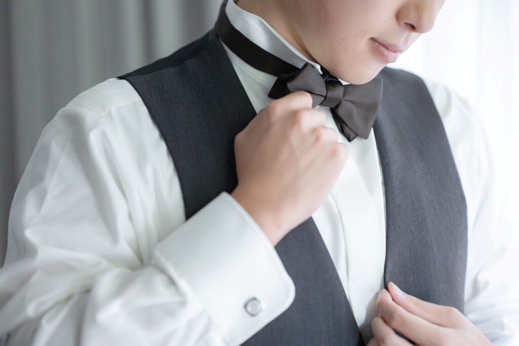 新郎のタキシードスタイル。フォーマルでシックな印象のブラックの蝶ネクタイとグレーのベストで、ワンランク上の洗練された大人の花婿に。
