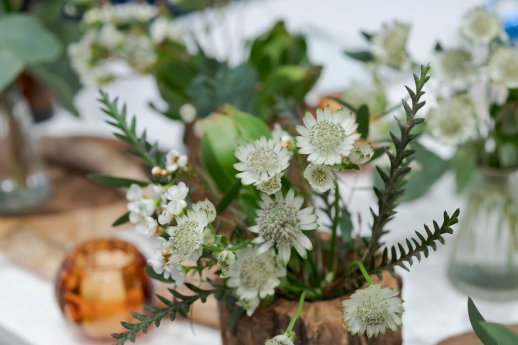 自然素材を活かしたウェディング装花。軽井沢の豊かな自然と調和する、ゲストテーブルを飾るナチュラルなアレンジメントです。木漏れ日の中でゆったりと過ごす、温かいパーティーを演出。
