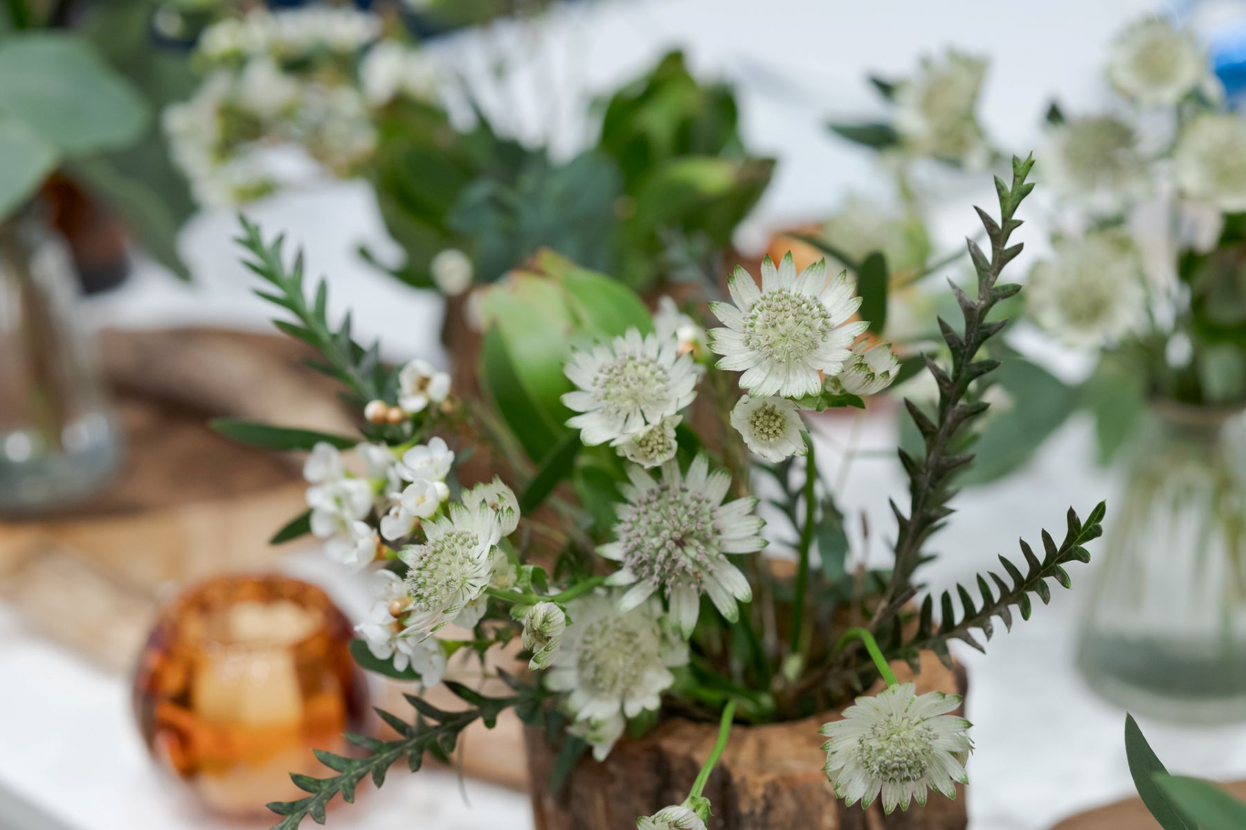 自然素材を活かしたウェディング装花。軽井沢の豊かな自然と調和する、ゲストテーブルを飾るナチュラルなアレンジメントです。木漏れ日の中でゆったりと過ごす、温かいパーティーを演出。