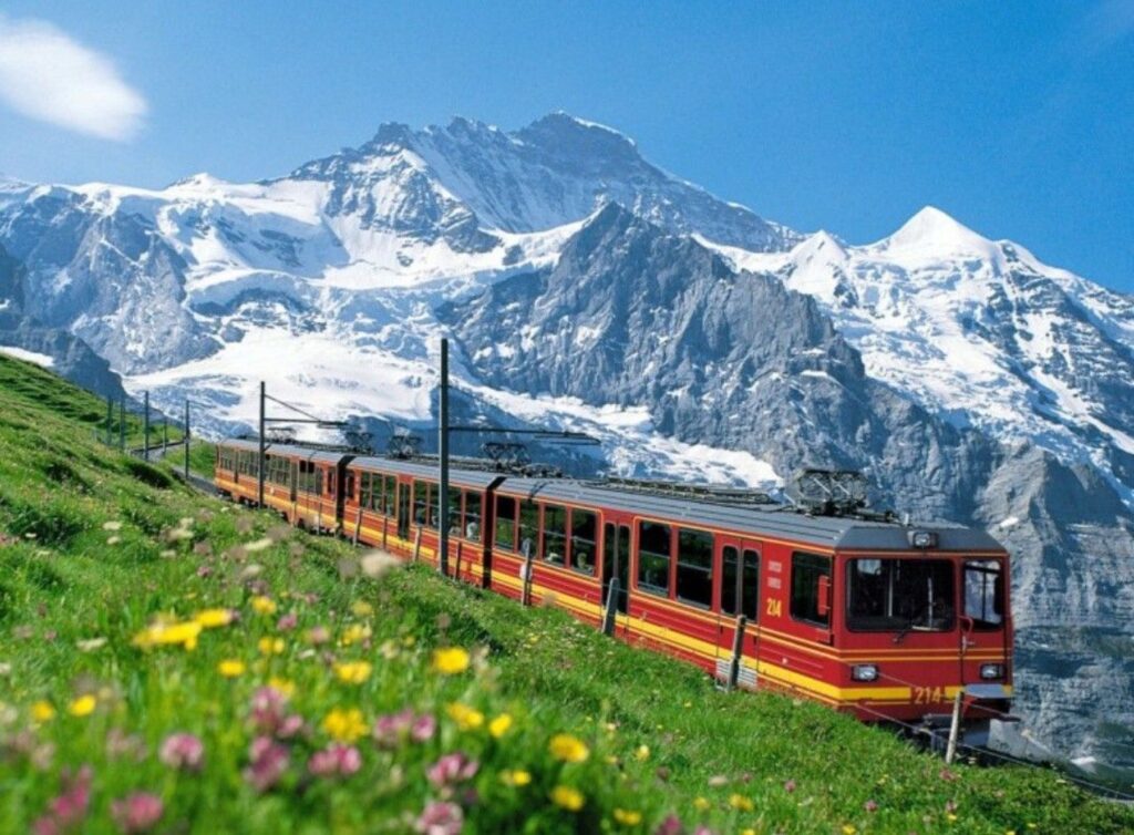 雄大なスイスの雪山と花畑を走る赤い列車。絵葉書のような絶景は、ハネムーンの特別な思い出に最適です。軽井沢の緑と共通する自然の美しさを持つスイスの魅力や、おすすめのモデルコースをご紹介。