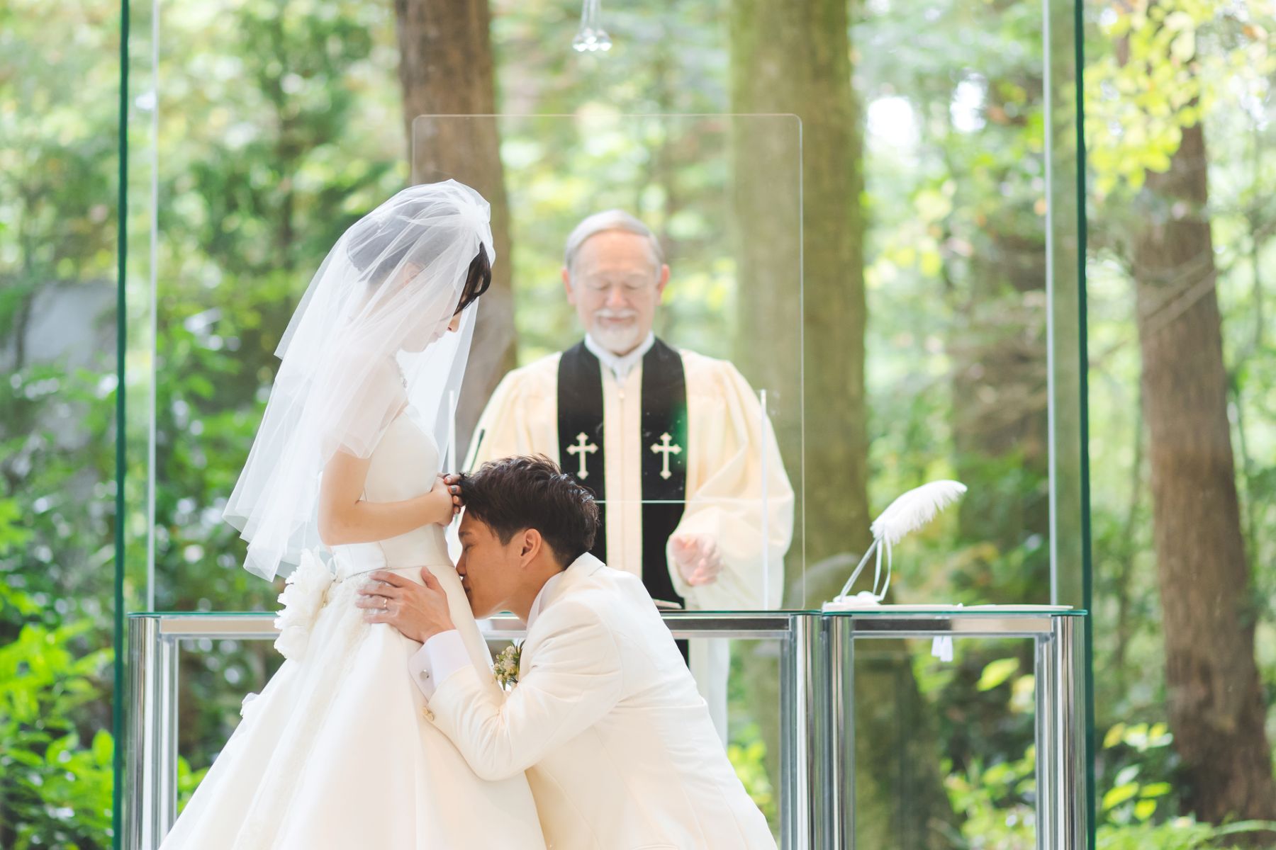 ガラス張りのチャペルに広がる軽井沢の自然の中で行われた、家族のはじまりを感じる感動的な挙式シーン。お腹の赤ちゃんに誓いを立てる瞬間は、マタニティウエディングならではの温かな時間です。