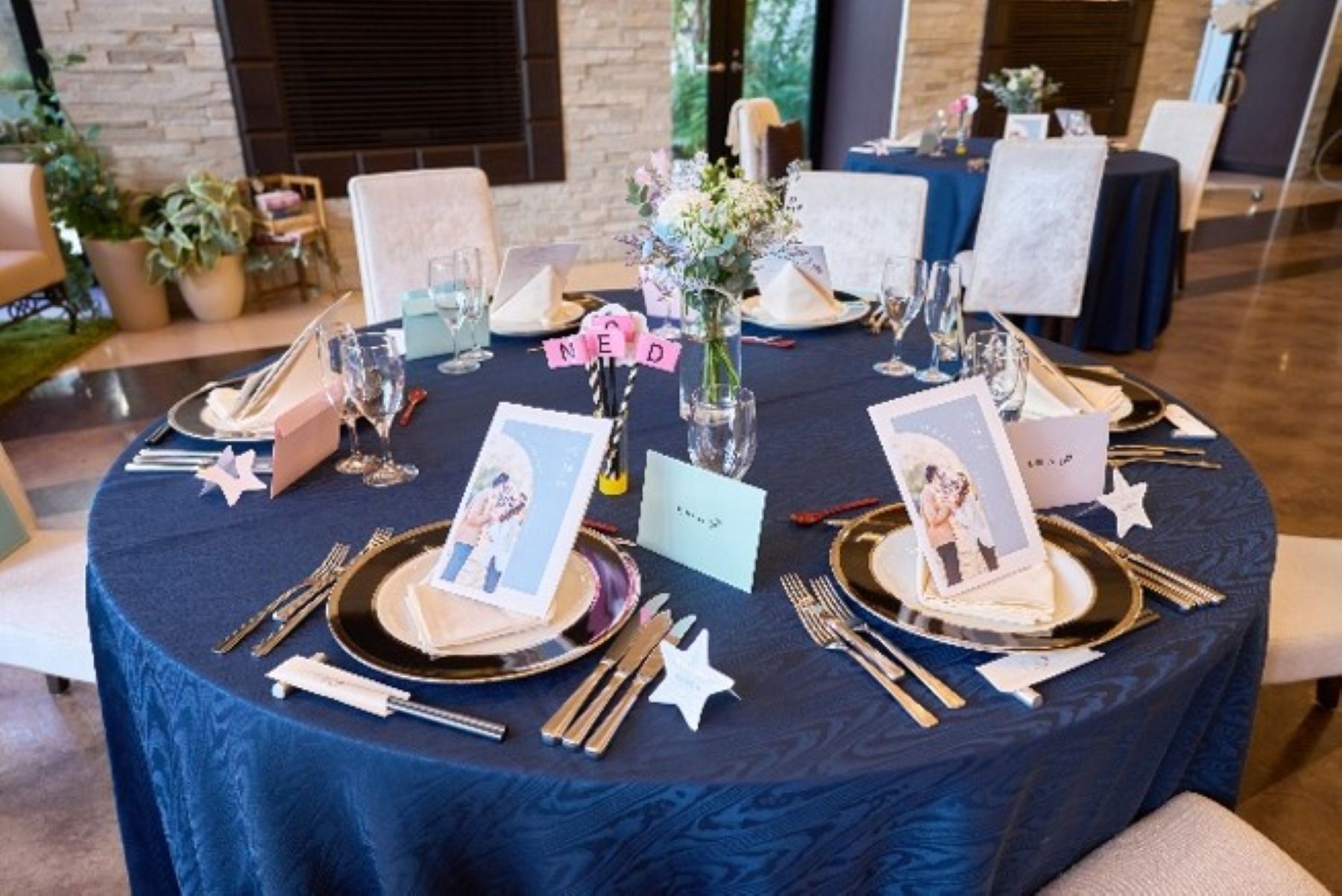 ネイビーに映える爽やかな花々。アネーリ軽井沢では、思い出の写真を添えたメニューや小物で、お二人らしい空間をご提案します。センス溢れるテーブル装花で、ゲストの記憶に残るおもてなしを