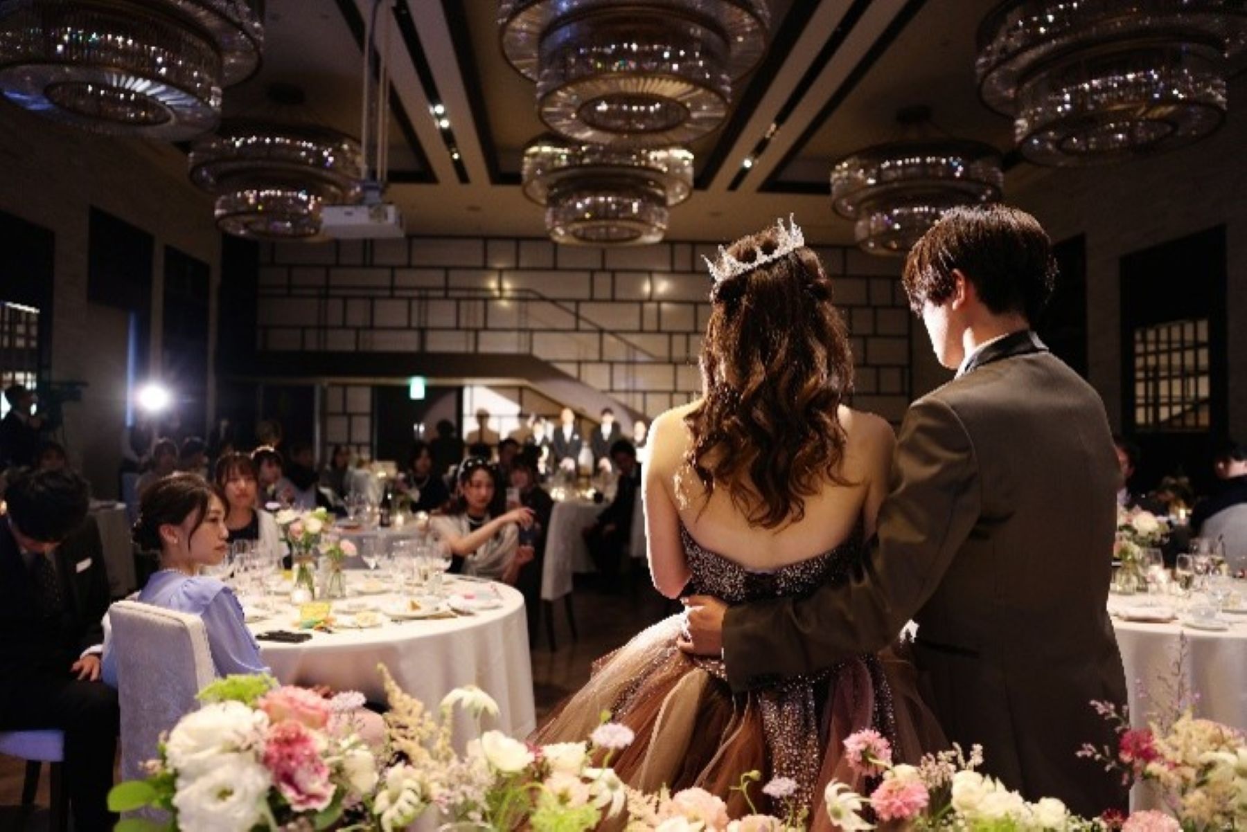 ゲストに見守られながら披露宴会場へ入場する新郎新婦。華やかなシャンデリアが輝く空間で行われるパーティーは、特別な一日をより印象的に演出します。アネーリ軽井沢では、大切なゲストと過ごす感動の披露宴や上質なウェディングパーティーが叶います。