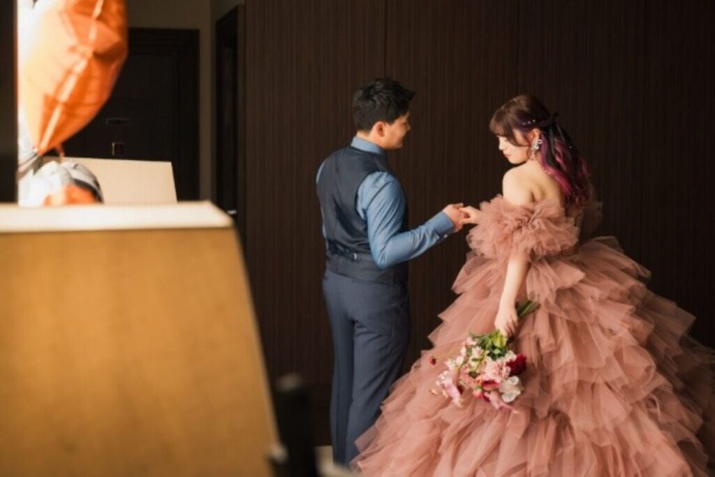 柔らかな光に包まれたお支度シーン。ふんわりとしたチュールドレスが動きに合わせて美しく広がり、写真映えを叶える一枚に。おふたりの自然な仕草や距離感が、特別な一日のはじまりを優しく演出します。