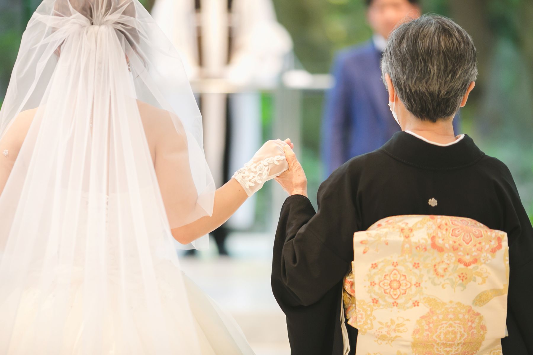 やわらかな光に包まれ、母と手を取り合いながら歩む感動のワンシーン。和装とドレスが織りなす美しい瞬間は、家族の絆や感謝の想いを伝える特別なセレモニーとして、多くの花嫁様に選ばれています。心に残る挙式演出の一例です。
