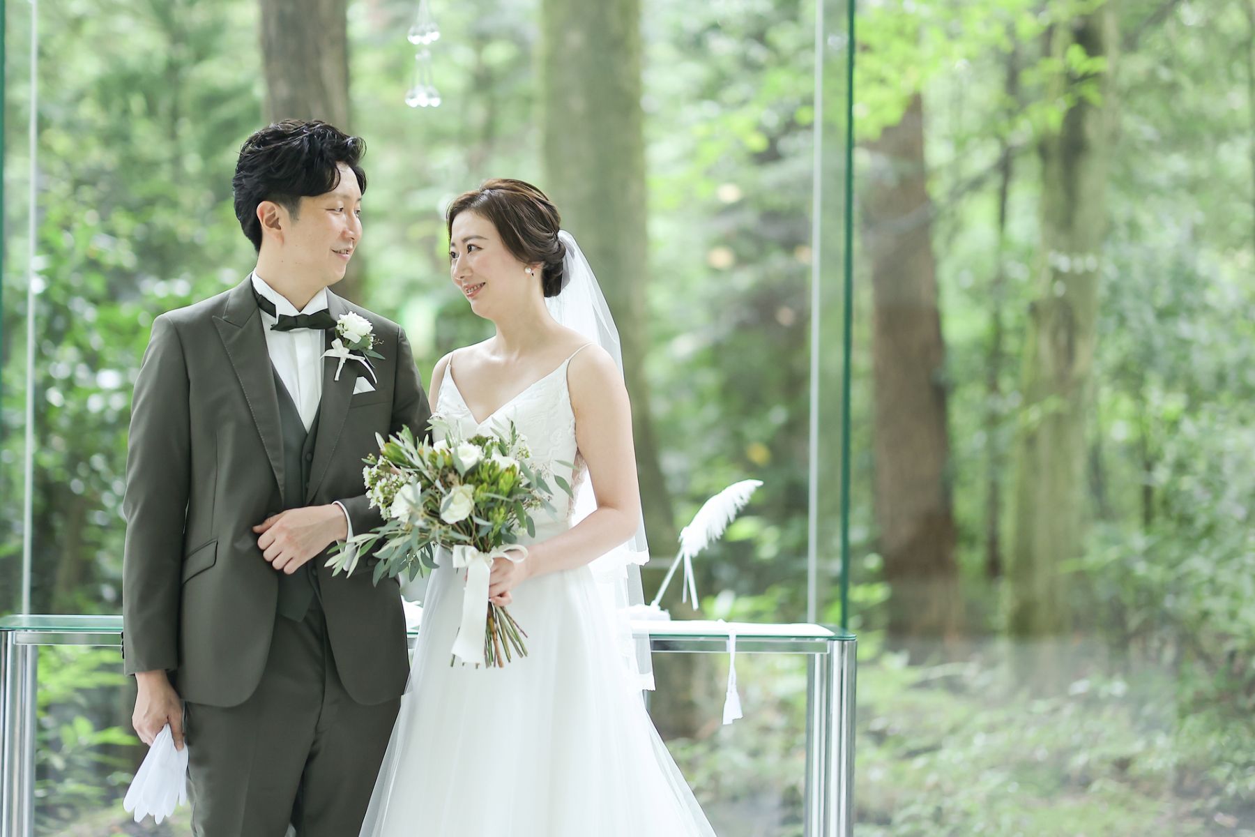 緑あふれる軽井沢の自然に包まれたガラス張りチャペルでの一枚。やわらかな自然光がドレスとブーケを美しく引き立て、ナチュラルで洗練された結婚式を演出します。前撮りや挙式シーンにも人気のロケーションです。