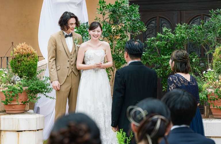 さいたま市の結婚式場アネーリ大宮。緑豊かなガーデンで、新郎新婦が笑顔で誓いの言葉を述べる。ゲストの温かい祝福に包まれたアットホームな人前式の瞬間。