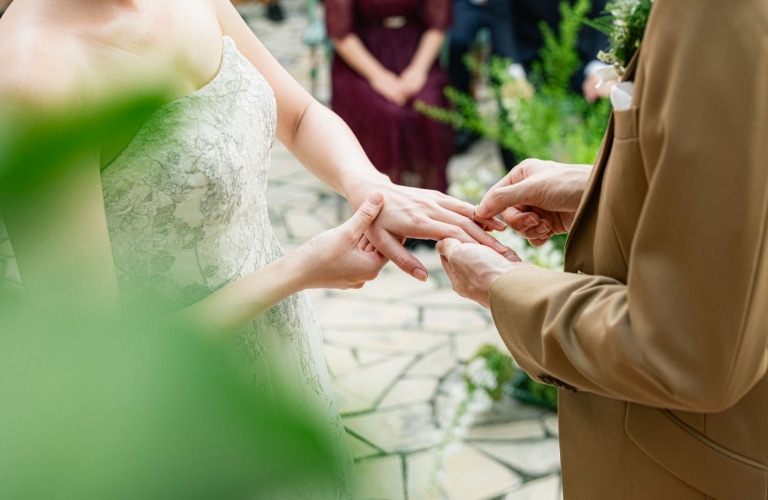さいたま市の結婚式場アネーリ大宮。緑と光に包まれたガーデン挙式で、新郎が新婦へ指輪を贈る神聖な瞬間。永遠の愛を誓い合う。