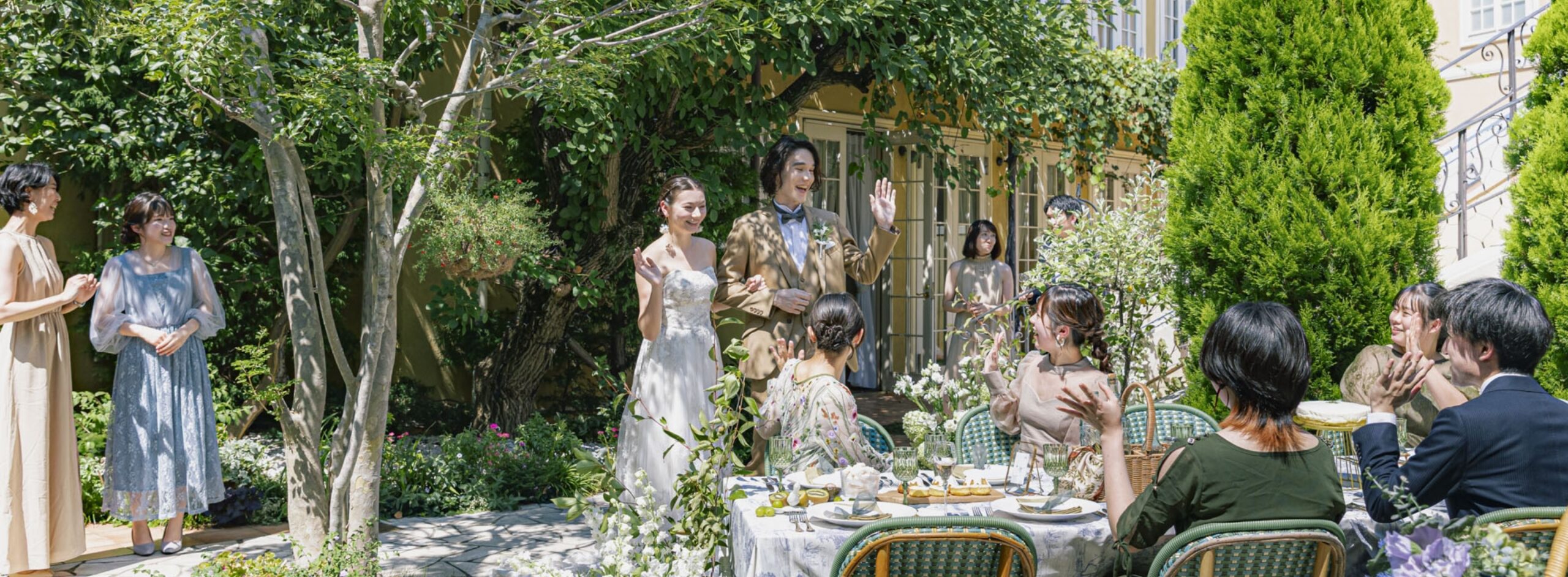 さいたま市の結婚式場アネーリ大宮。緑溢れるガーデンでゲストと笑顔で会話を楽しむ新郎新婦。距離感が近く、自然体で過ごせるアットホームなパーティ。