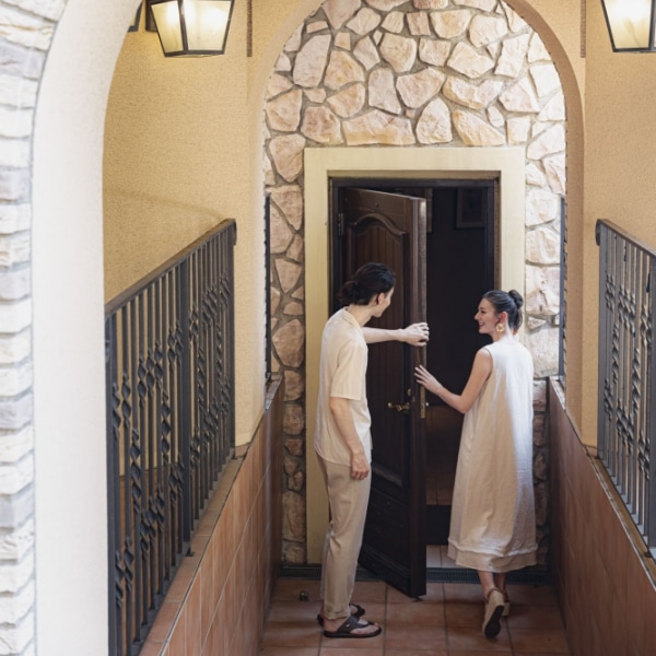 さいたま市の結婚式場アネーリ大宮「ノス・ド・フロマン」。緑のアーチの下、カメラを片手に思い出を巡る二人。記念日に再訪し、ゆったりと過ごす大人のデート。