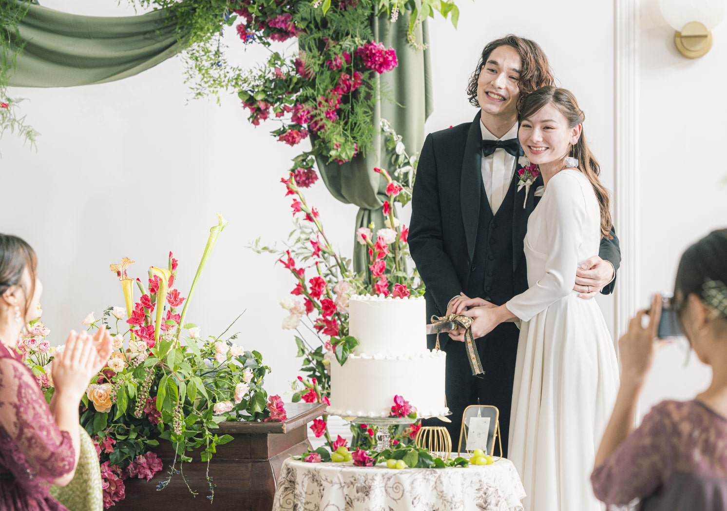 さいたま市の結婚式場アネーリ大宮。華やかな装花が彩る高砂でのケーキ入刀。ゲストの拍手と笑顔に包まれ、幸せを分かち合う感動の披露宴シーン。