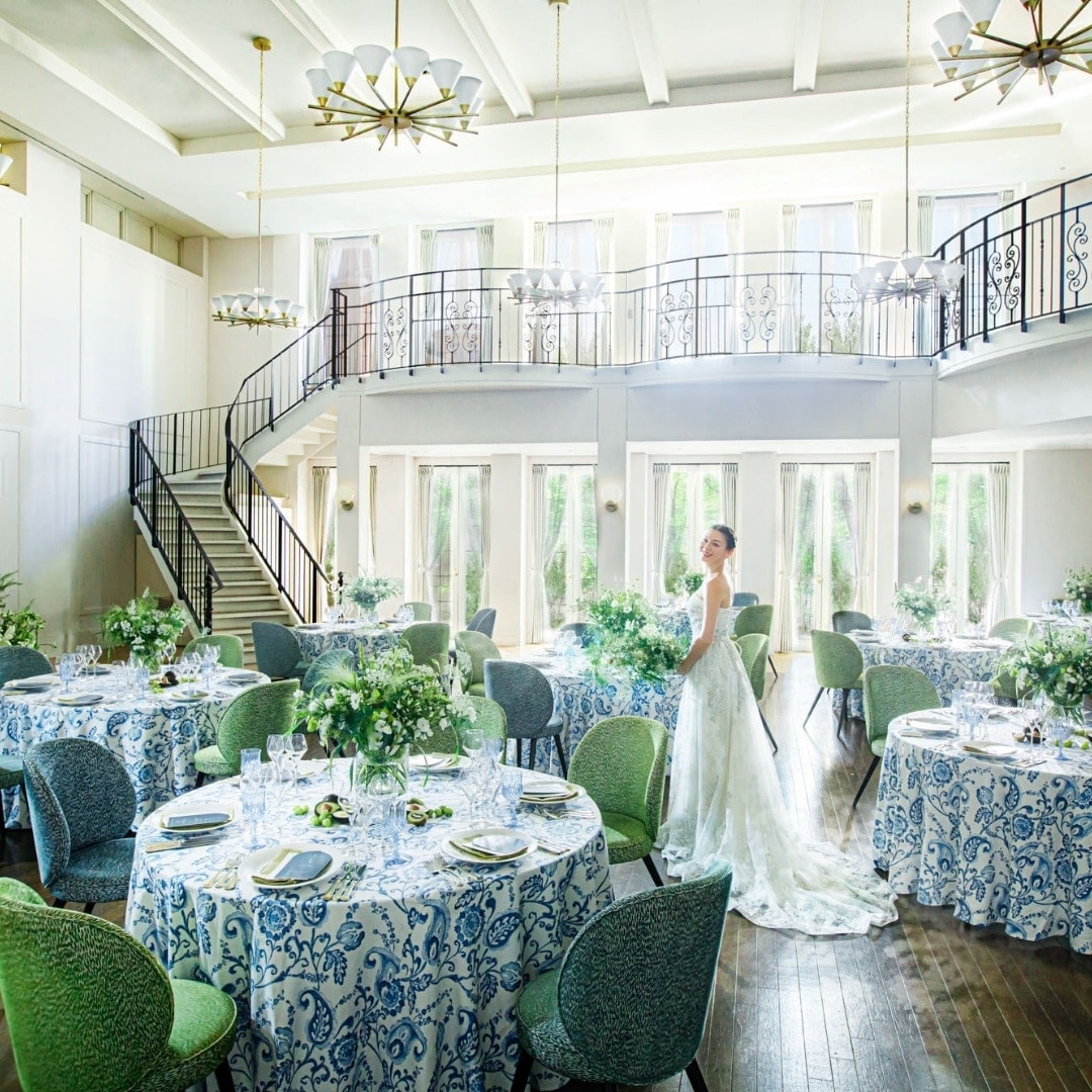 さいたま市の結婚式場アネーリ大宮。自然光が注ぐ白亜の披露宴会場。憧れの大階段と爽やかな青のコーディネートが映える、開放感あふれるパーティ空間。