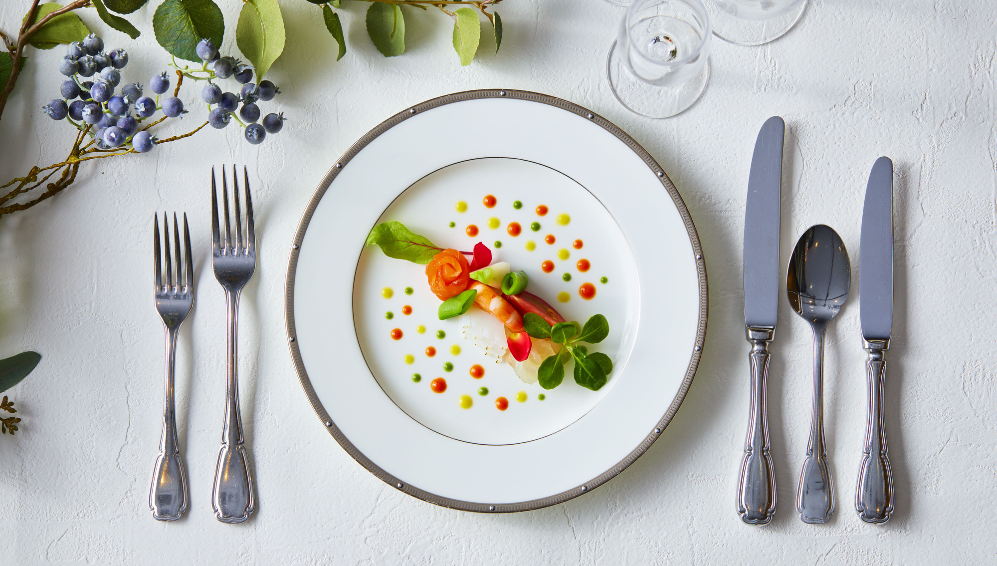 さいたま市の結婚式場アネーリ大宮が提供する、彩り豊かなソースと海老のフレンチ前菜。カトラリーが並ぶ美しいテーブルセッティング。