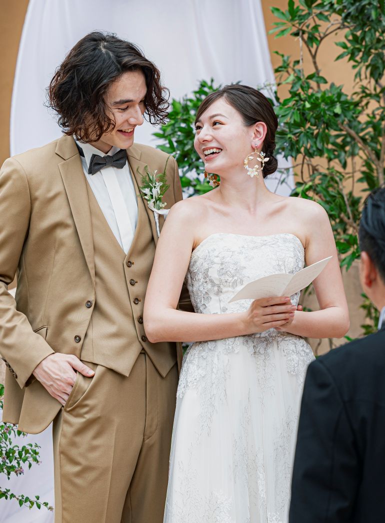 さいたま市の結婚式場アネーリ大宮。ガーデン挙式で、笑顔で見つめ合い愛を誓う新郎新婦。温かい祝福に満ちた、感動的な挙式のワンシーン。