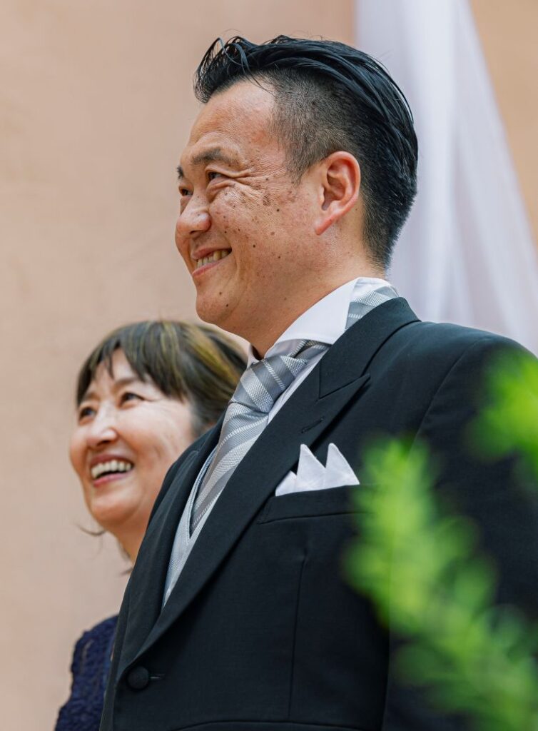 さいたま市の結婚式場アネーリ大宮。ガーデン挙式で、新郎新婦を最高の笑顔で見守る両親。温かい愛情と祝福に満ちた感動の瞬間。